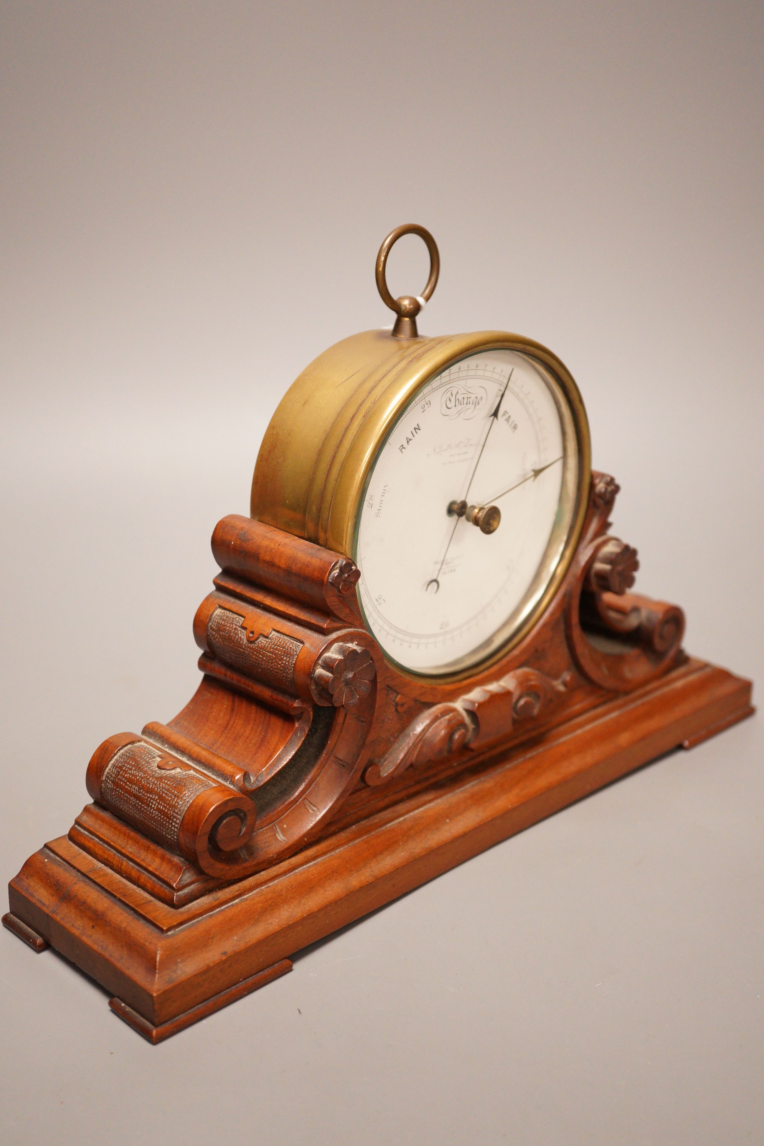 A Negretti & Zambra brass cased barometer on carved walnut stand, 31cm wide